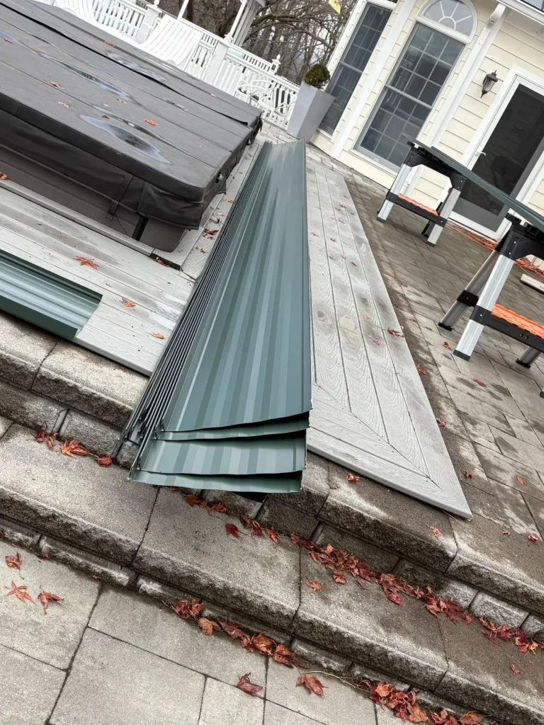 Hand-made Hartford Green metal roof trim and standing seam panels staged on a porch in Sparta, NC