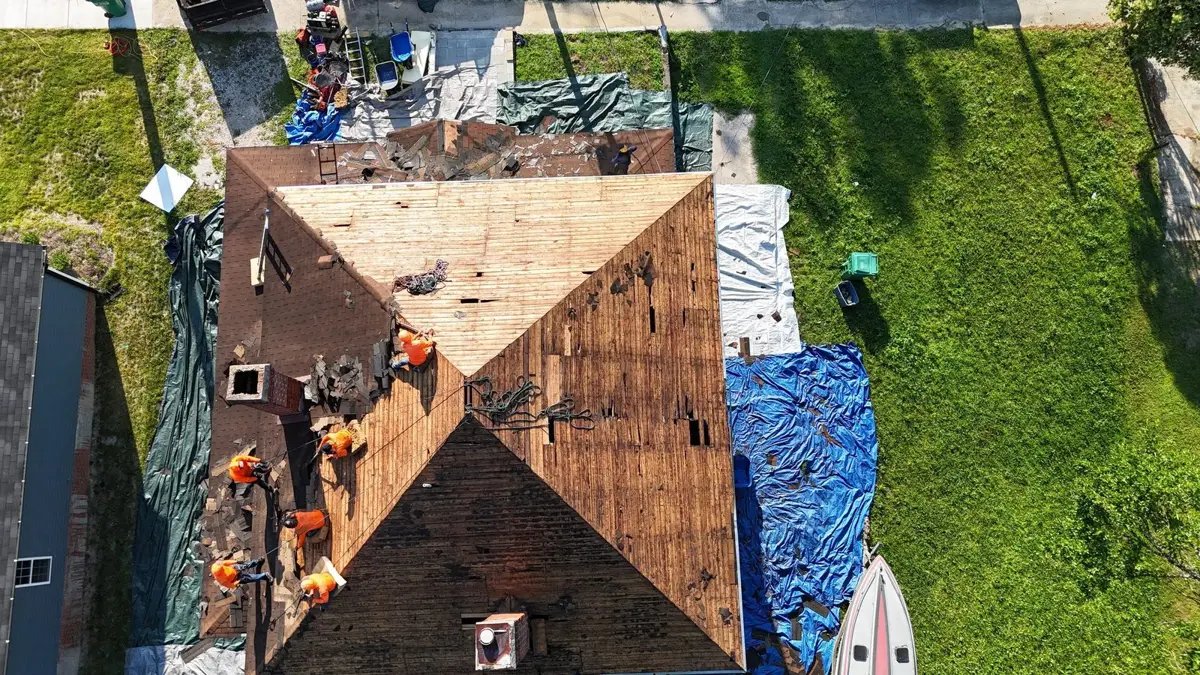 Roofing crew stripping a storm-damaged roof in High Point, NC, seen from a drone
