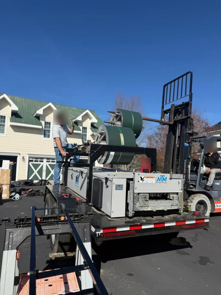 Statewide Roofing's standing seam machine roll-forming Hartford Green metal roof panels on site in Sparta, NC
