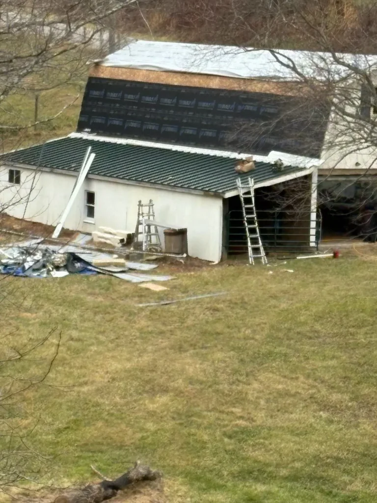 Gambrel barn in Sparta, NC mid-replacement, with new standing seam going on below the old roof