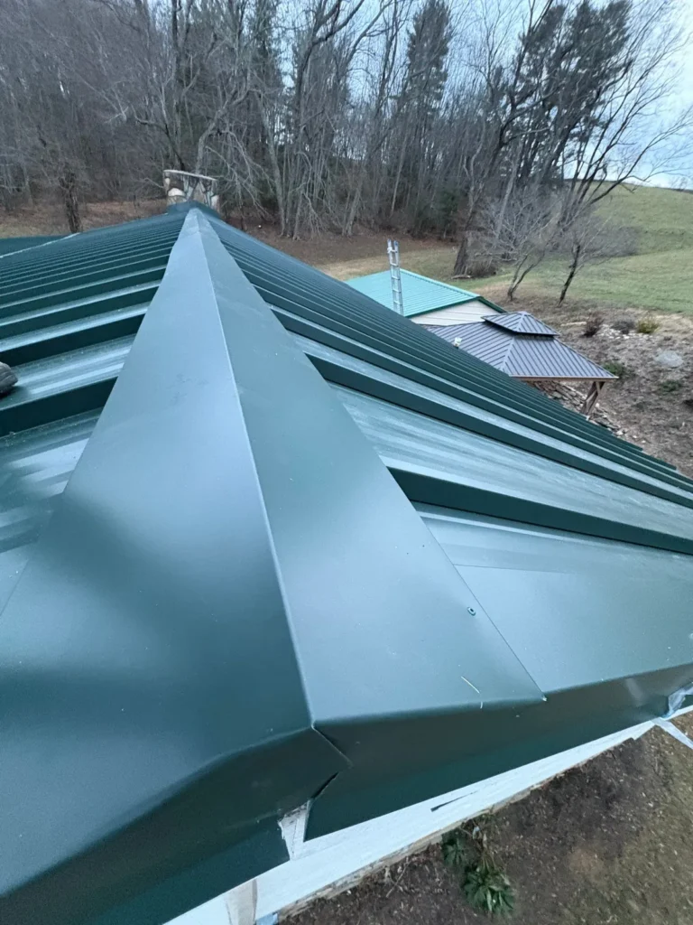 Hand-made hip cap trim on a dark green standing seam metal roof in Sparta, NC