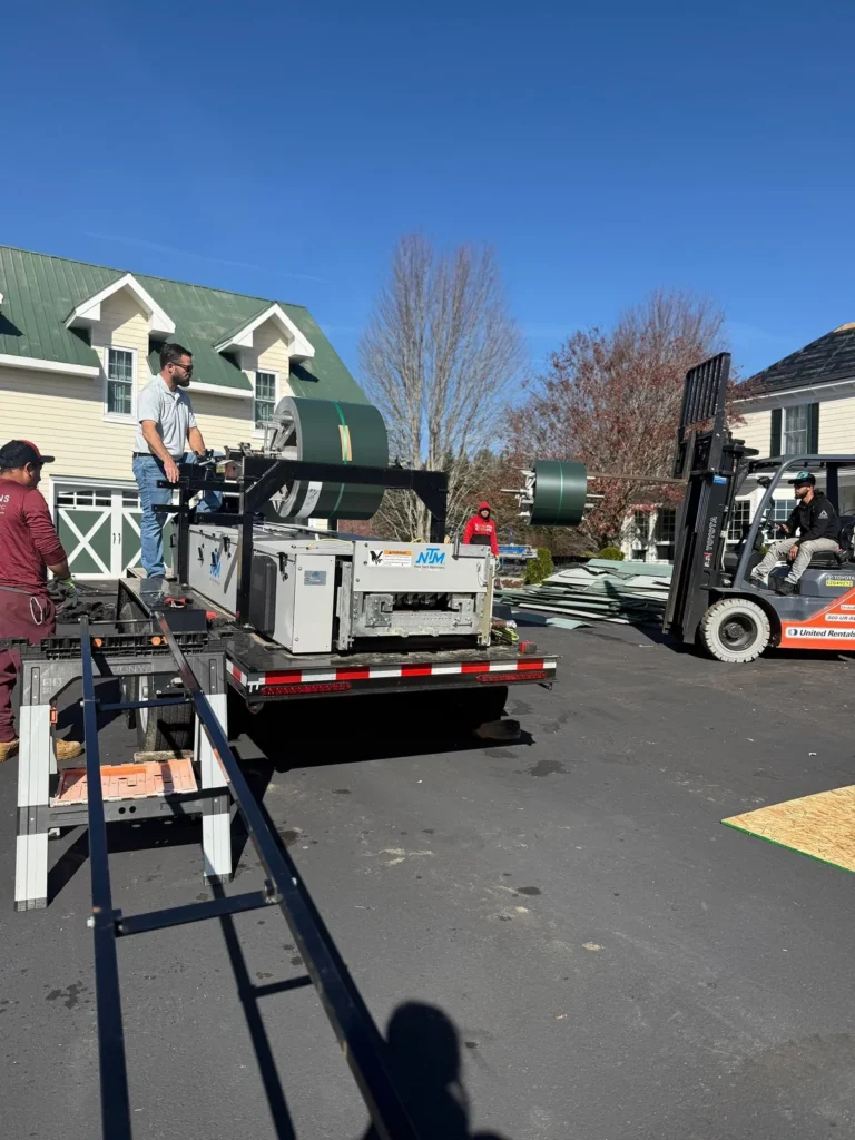 Statewide Roofing standing seam roll former running custom metal roof panels on site in Sparta, NC
