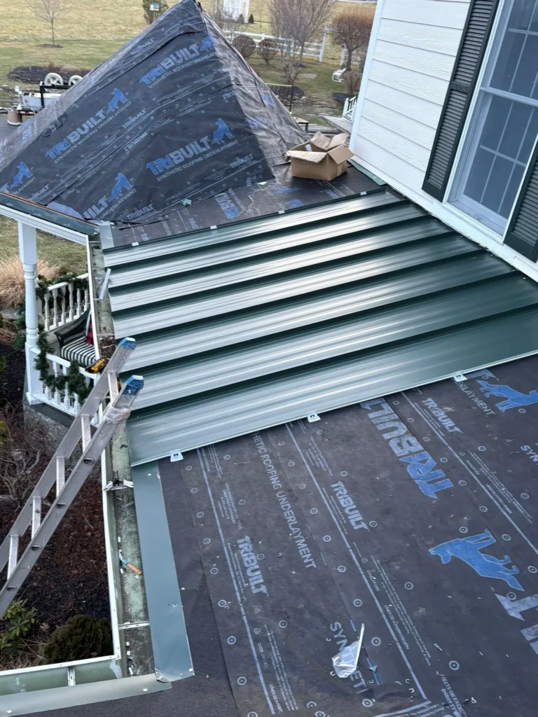 Standing seam metal roof panels going on over synthetic underlayment on a porch roof in Sparta, NC