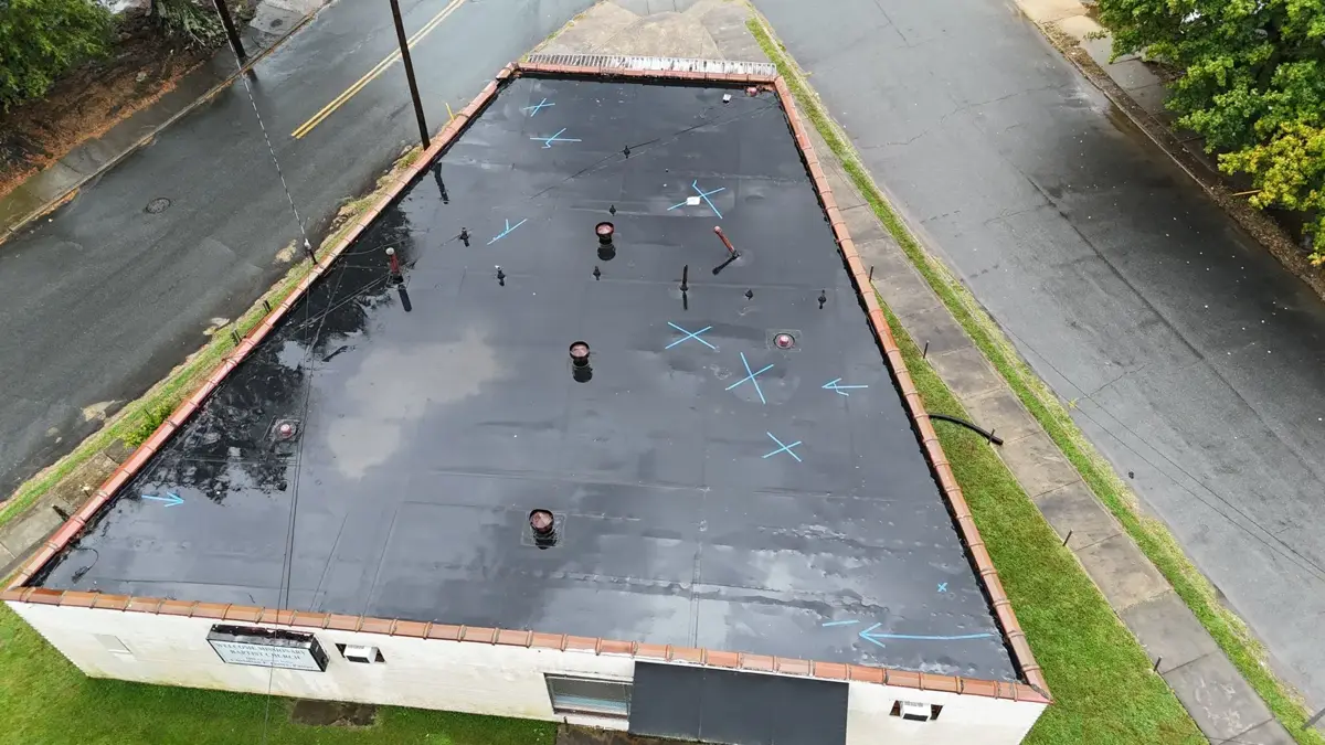 Aerial drone view of a church flat roof with old black membrane and ponding water in Winston-Salem, NC